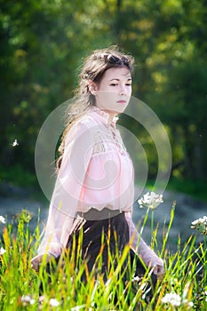 Young woman on a summer sunny day walking in field of flowers