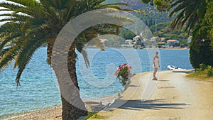 Young woman on summer vacation rides an electric skateboard down an empty road.