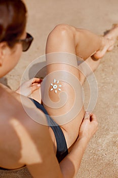 Young Woman With Sun Shape On The Leg. Sun Protection Sunscreen On Her Smooth Tanned Legs.