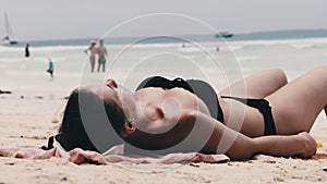 Young Woman Sunbathes on a Paradise Sandy Beach Lying in Black Bikini near Ocean
