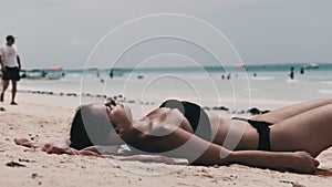 Young Woman Sunbathes on a Paradise Sandy Beach Lying in Black Bikini near Ocean