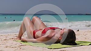 Young Woman Sunbathes on a Paradise Sandy Beach Lying in Red Swimsuit near Ocean