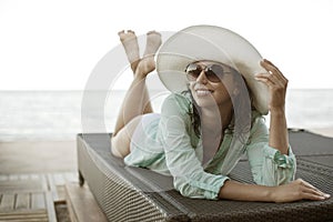 Young woman sunbathes sitting on sunbed.