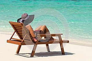 Young woman sunbathing on lounger at tropical beach