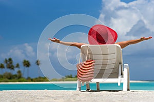 Young woman sunbathing on lounger at tropical beach.