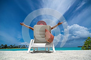 Young woman sunbathing on lounger at tropical beach