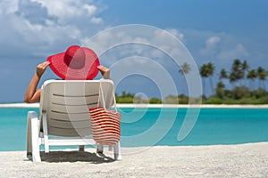 Young woman sunbathing on lounger at tropical beach