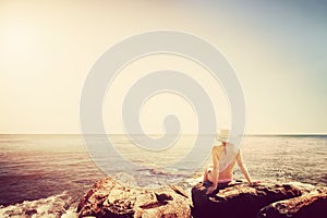 Young woman sunbathing on rocky beach. Vintage