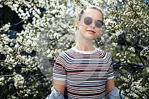 Young woman in sunglasses on background of blossoming apple tree
