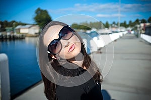 Young woman in sunglasses blow a kiss at a wharf