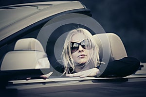 Young woman in sunglasses driving convertible car