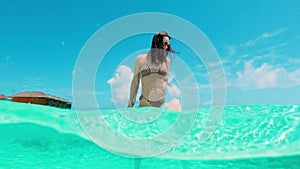Young woman in sunglasses has fun standing in ocean water