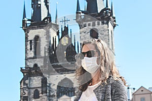 Young woman with sunglasses and medical face mask photographed in front of the Church of Our Lady before Tyn in Prague, Czech