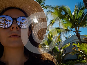 young woman in sunglasses and a straw hat on a tropical island.