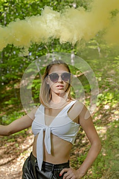 Young woman in sunglasses and summer clothes using smoke bomb