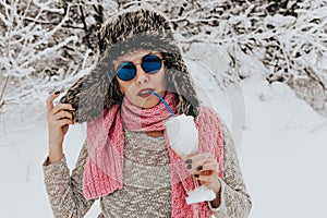 Young woman in sunglasses and a wine glass filled with snow. Woman misses relaxing on the beach