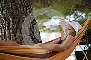 Young woman with a sunhat lying and enjoying life in a hammock