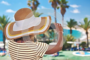 Young woman in sunhat making photo of amazing sea view with his smartphone photo
