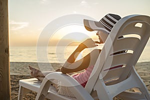 Young woman with sunhat sitting on a plastic beach chair