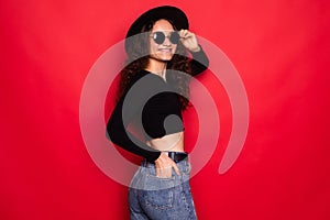 Young woman in sunhat and sunglasses enjoying life isolated over red background