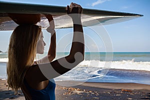 Young woman with surfboard walk on black sand beach