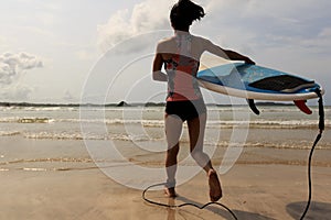 Young woman surfer with white surfboard running to the sea