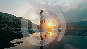 Young woman surfing during summer sunrise at sea.