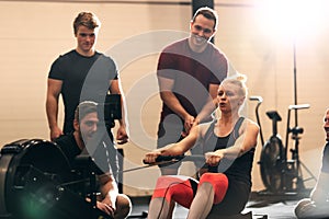 Young woman surrounded by friends while using a rowing machine