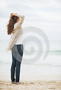 Young woman in sweater relaxing on lonely beach