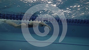 Young woman swimmer floating butterfly stroke in clear water pool underwater