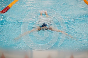 Young woman swimmer swims in swimming pool