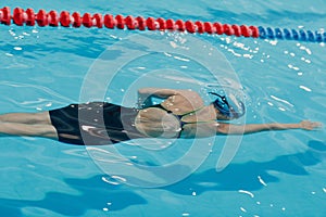 Young woman swimmer swims in swimming pool