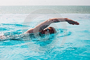 Young Woman swimming Crawl in a pool with sea view