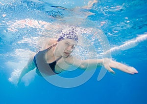 Young woman swimming the front crawl in a pool, taken underwater