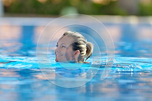 Young woman swimming in the pool on a warm summer day