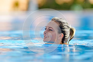 Young woman swimming in the pool on a warm summer day