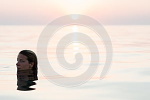 Young woman swimming in the sea in sunset