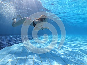 Young woman swimming underwater in the pool