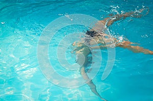 Young woman swimming underwater in swimming pool