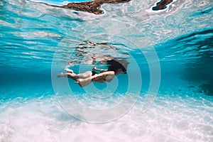 Young woman swimming underwater in the tropical blue ocean with sand