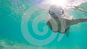 Young woman is swimming underwater and wearing a mask