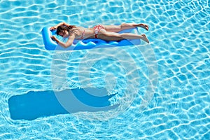 Young woman in swimsuit bakes lying on inflatable mattress