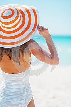 Young woman in swimsuit beach hat looking into distance