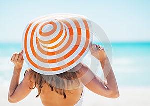 Young woman in swimsuit beach hat looking into distance