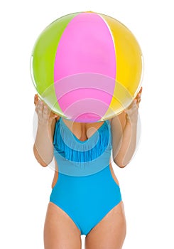 Young woman in swimsuit hiding behind beach ball