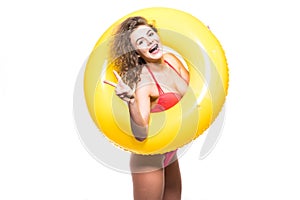 Young Woman in swimsuit with an inflatable ring and hand showing victory gesture isolated over white background