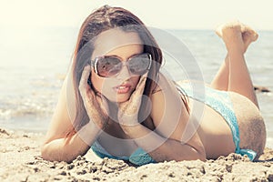 Young woman in swimsuit on the sand with sunglasses