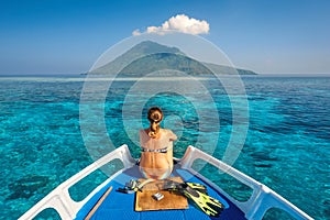 Young woman in swimsuit sit on boat with a mask and flippers loo