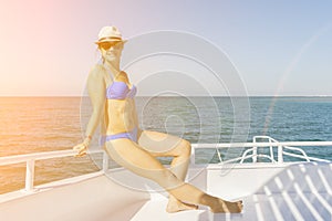 Young woman in swimsuit standing on yacht at sunny day. girl in a blue swimsuit sunning on a yacht in the open sea on a sunny day