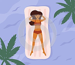Young woman in swimsuit sunbathing swimming on air mattress in sea or pool